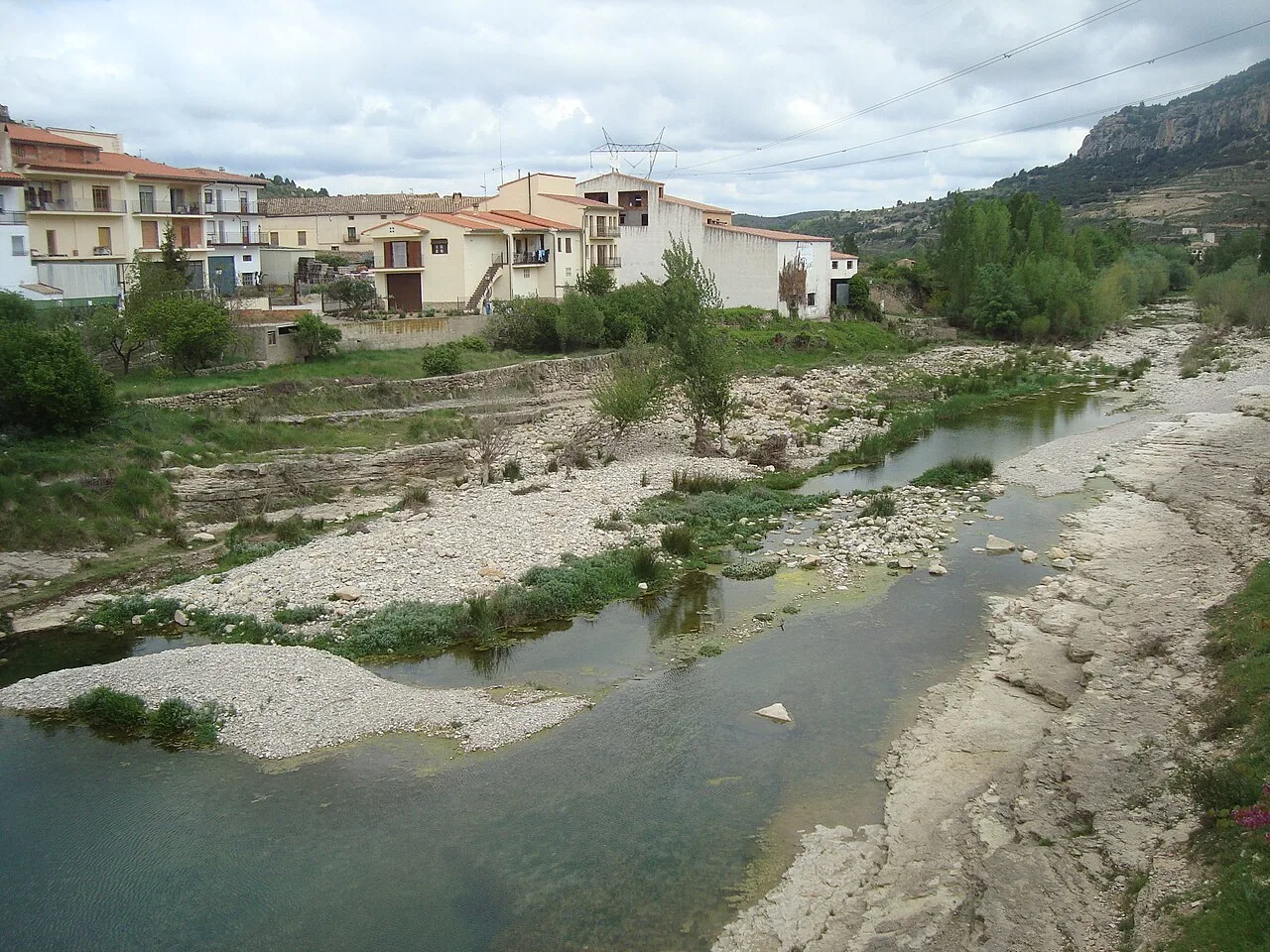 Río Caldes con casas y vegetación en Forcall, Castellón.