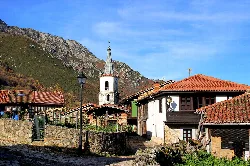 Village with church and traditional houses in a mountainous landscape.
