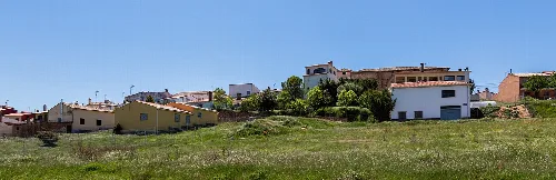 Verstreute Häuser auf einer grünen Landschaft mit sanften Hügeln in Arcos de la Sierra.