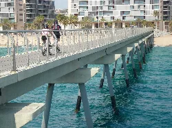 Lange Brücke über das Meer mit Spaziergängern und Radfahrern.