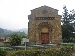 Stone church with decorative arch and wooden door in Quirós.
