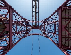 Perspectiva desde abajo del puente de Vizcaya con estructura de hierro roja y cielo azul.