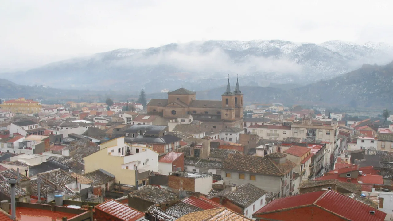 View of rooftops and churches in Cantoria with snow-capped mountains in the background.