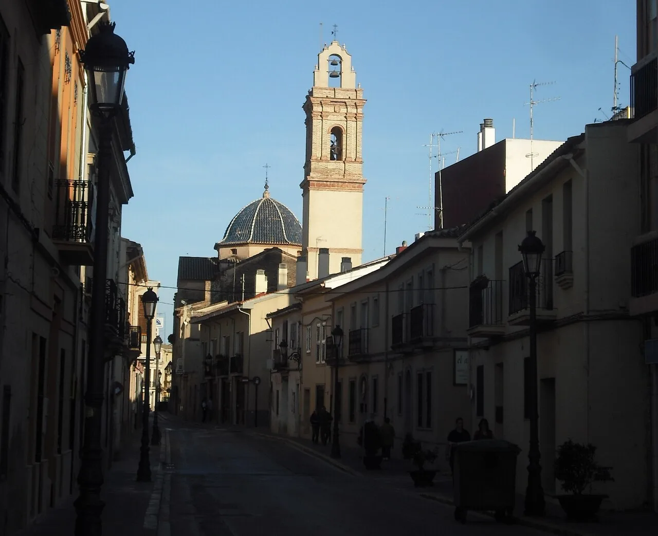 Iglesia de Godella vista desde la calle Mayor con edificios y farolas.