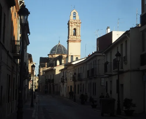 Kirche in Godella gesehen von Calle Mayor mit Gebäuden und Straßenlaternen.