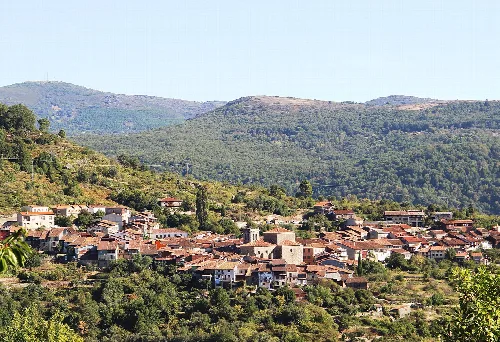 Panoramablick auf Mogarraz mit Häusern und Bergen im Hintergrund.