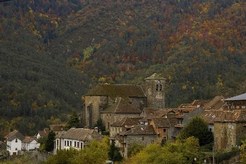 Ansó mit gotischer Kirche und Häusern in einer Herbstlandschaft.