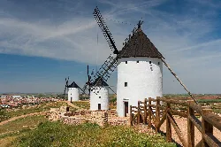 White windmills with blades in an open field.