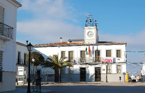 Weißes Gebäude mit Uhr und Flaggen in Monroy, Cáceres.