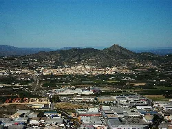 Paisaje con pueblo, montañas y castillo en la distancia.