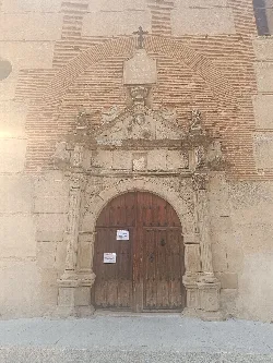 Church entrance with brick arch and sculptural details in Collado de Contreras.