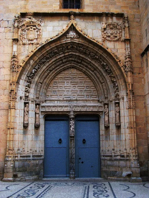 Kirchentür mit gotischem Bogen und Skulpturen am Eingang.