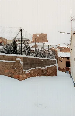 Vista de casas y un castillo en Sisamón con nieve en 2020.