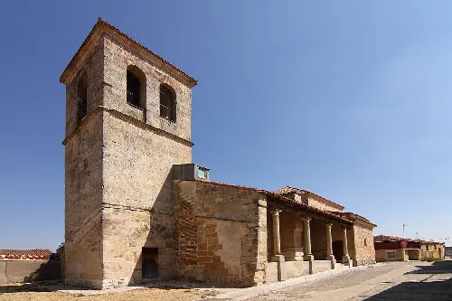 Church of the Exaltation of the Cross in Palencia de Negrilla with tower and stone façade.