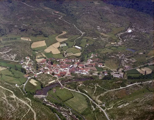 Luftaufnahme von Oroz-Betelu mit Häusern, Straßen und Feldern in einer bergigen Landschaft.