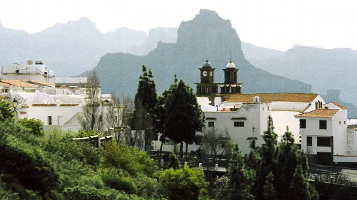 Weiße Gebäude und eine Kirche in Artenara mit Bergen im Hintergrund