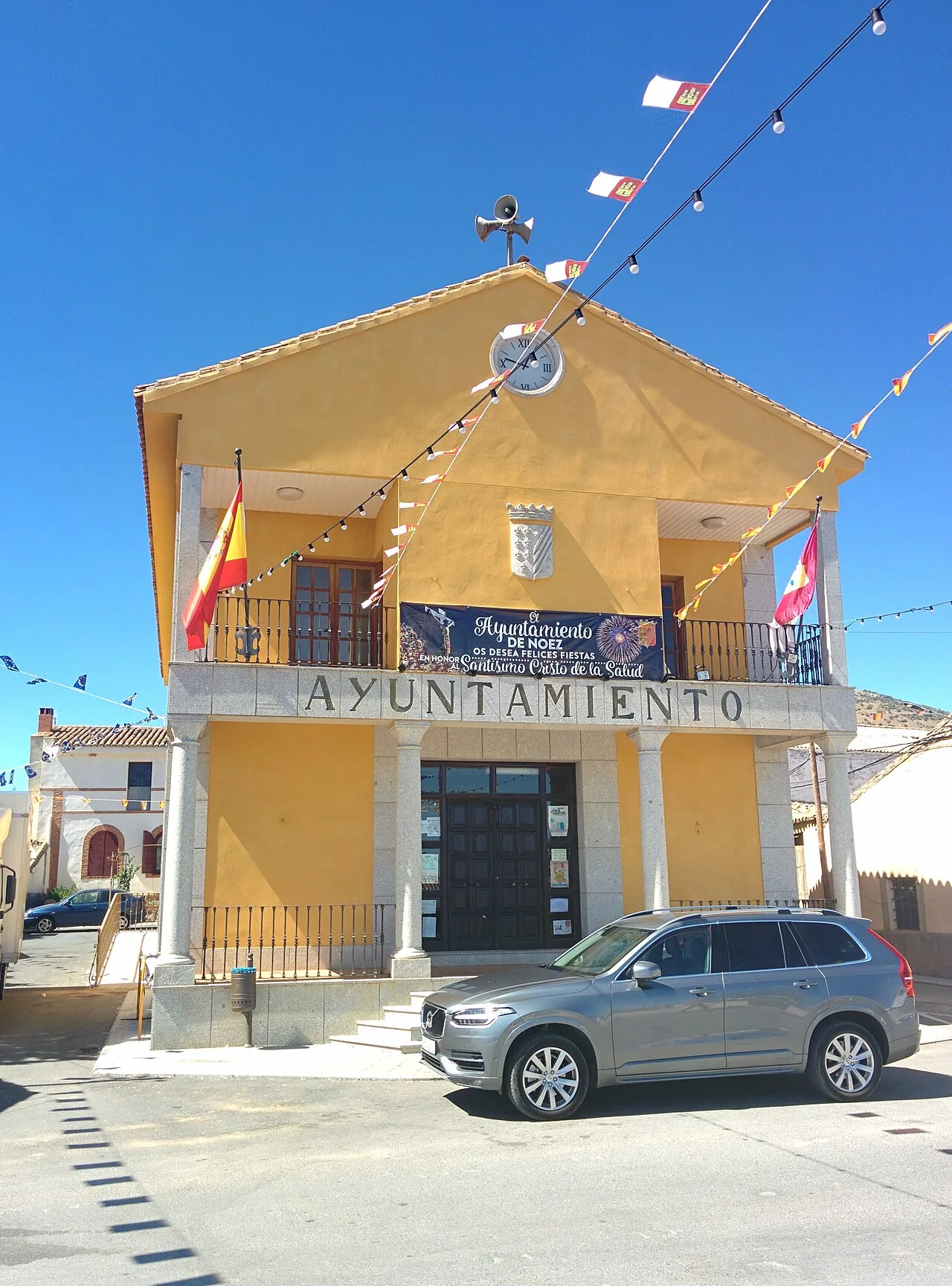 Yellow building with a town hall sign and a car parked in front.