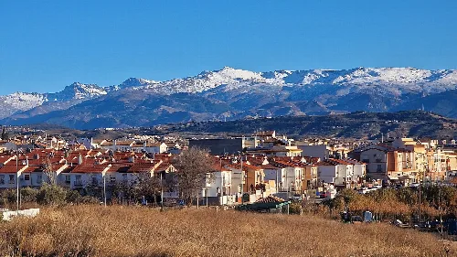 Blick auf Peligros mit schneebedeckten Bergen im Hintergrund