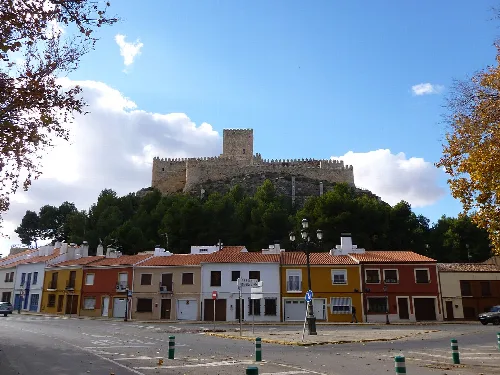 Castillo en lo alto de una colina con casas coloridas en primer plano.