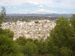 Blick auf Liria mit Bäumen im Vordergrund und Bergen im Hintergrund.