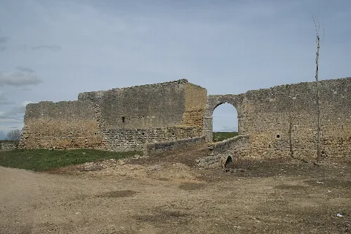 Ruinas de un castillo con arco de entrada y muro de piedra.