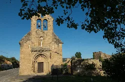 Stone church in a mountainous landscape with trees and blue sky.