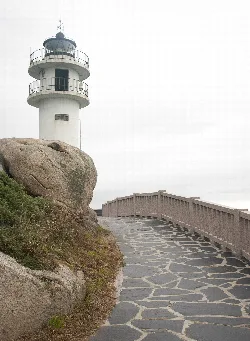 Stone pathway with railing leading to a lighthouse on the coast of Xove.