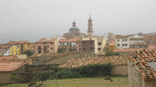 Blick auf Häuser und eine Kirche in Sarrión, Teruel, an einem bewölkten Tag.